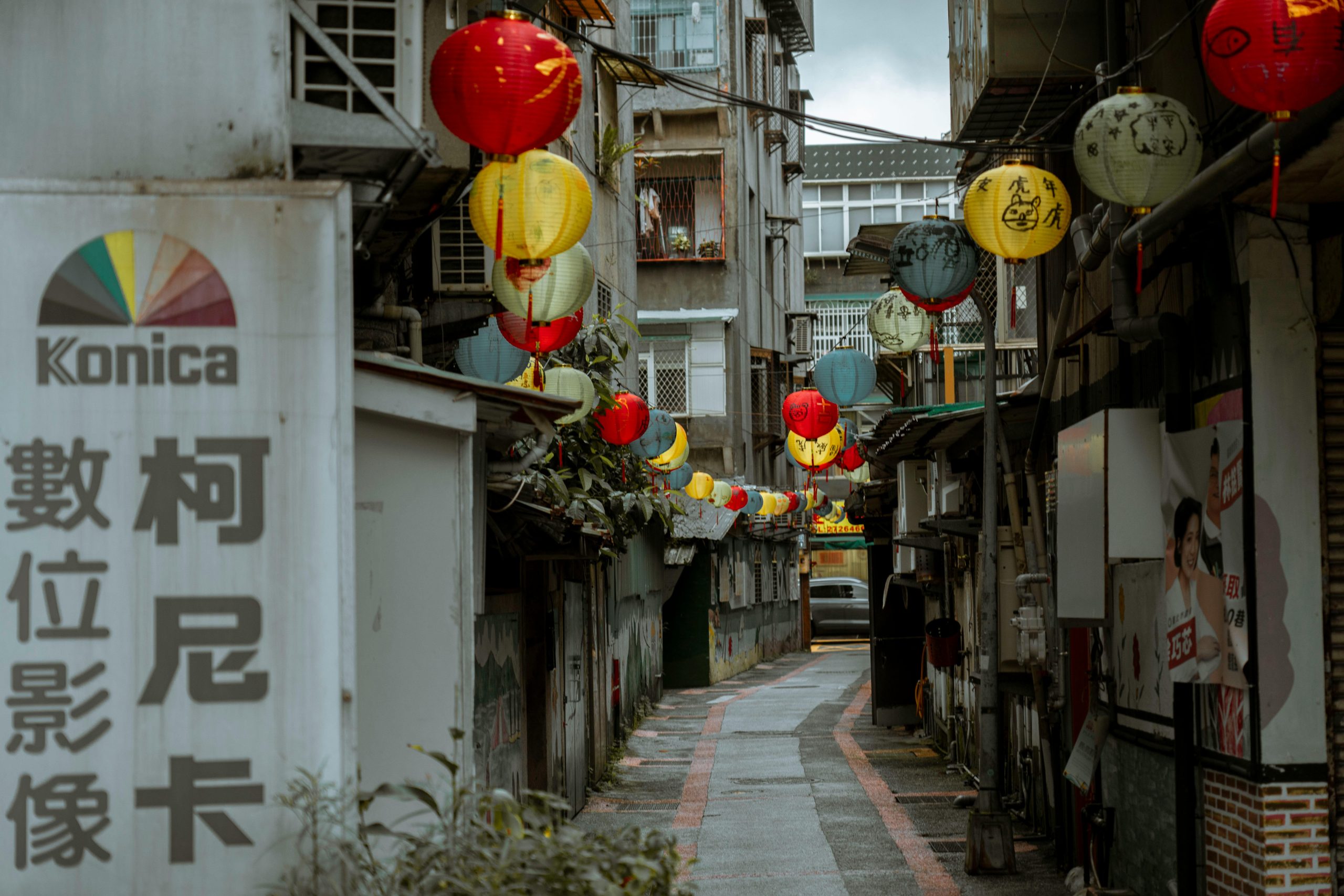 A charming narrow street in Hoi An Ancient Town at night, illuminated by countless colorful silk lanterns hanging overhead. People are strolling leisurely, and traditional yellow buildings line the street.