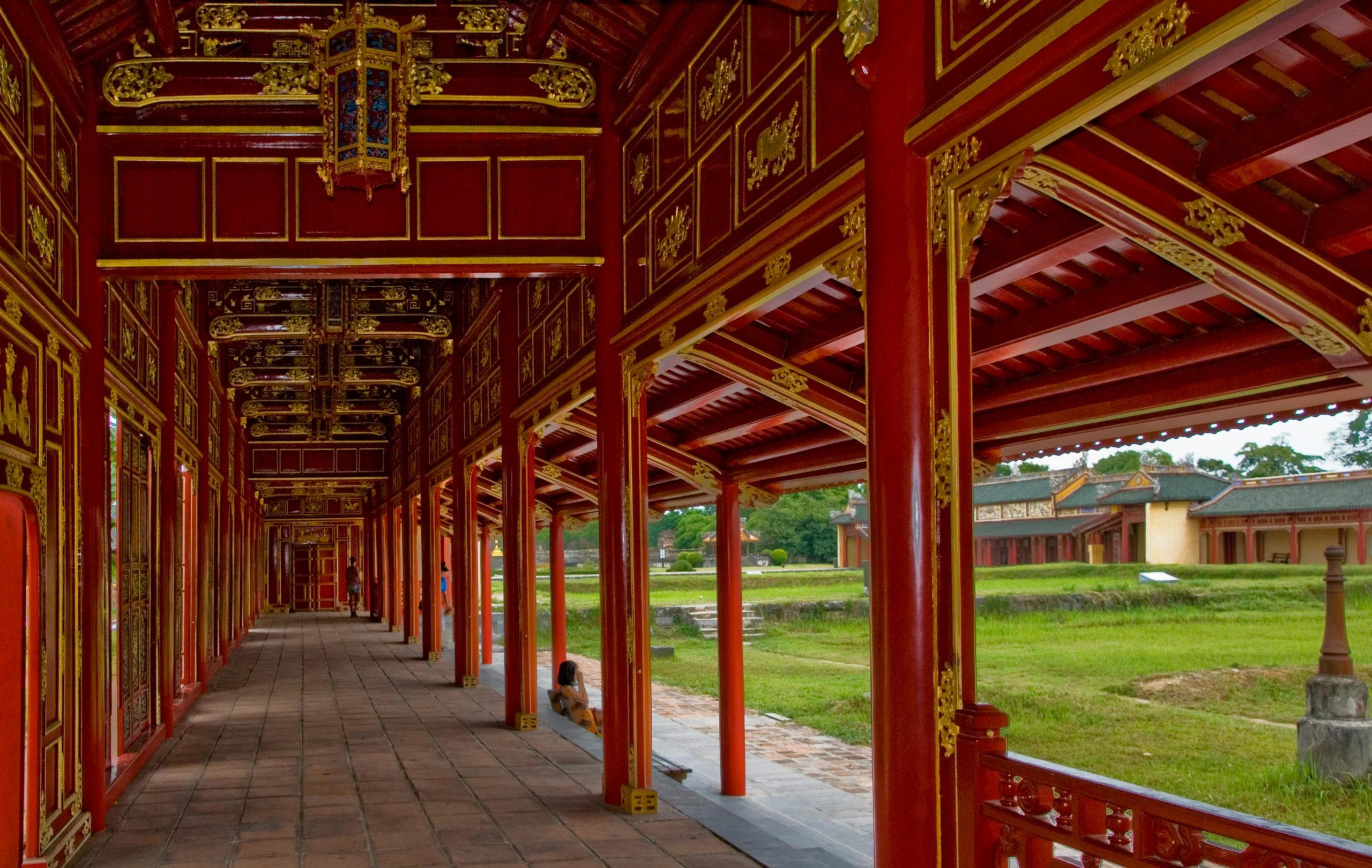 A grand, detailed shot of the Ngo Mon Gate (Meridian Gate) at the Imperial City in Hue, Vietnam, with traditional Vietnamese imperial architecture, vibrant red and gold colors, and people entering through the gate.
