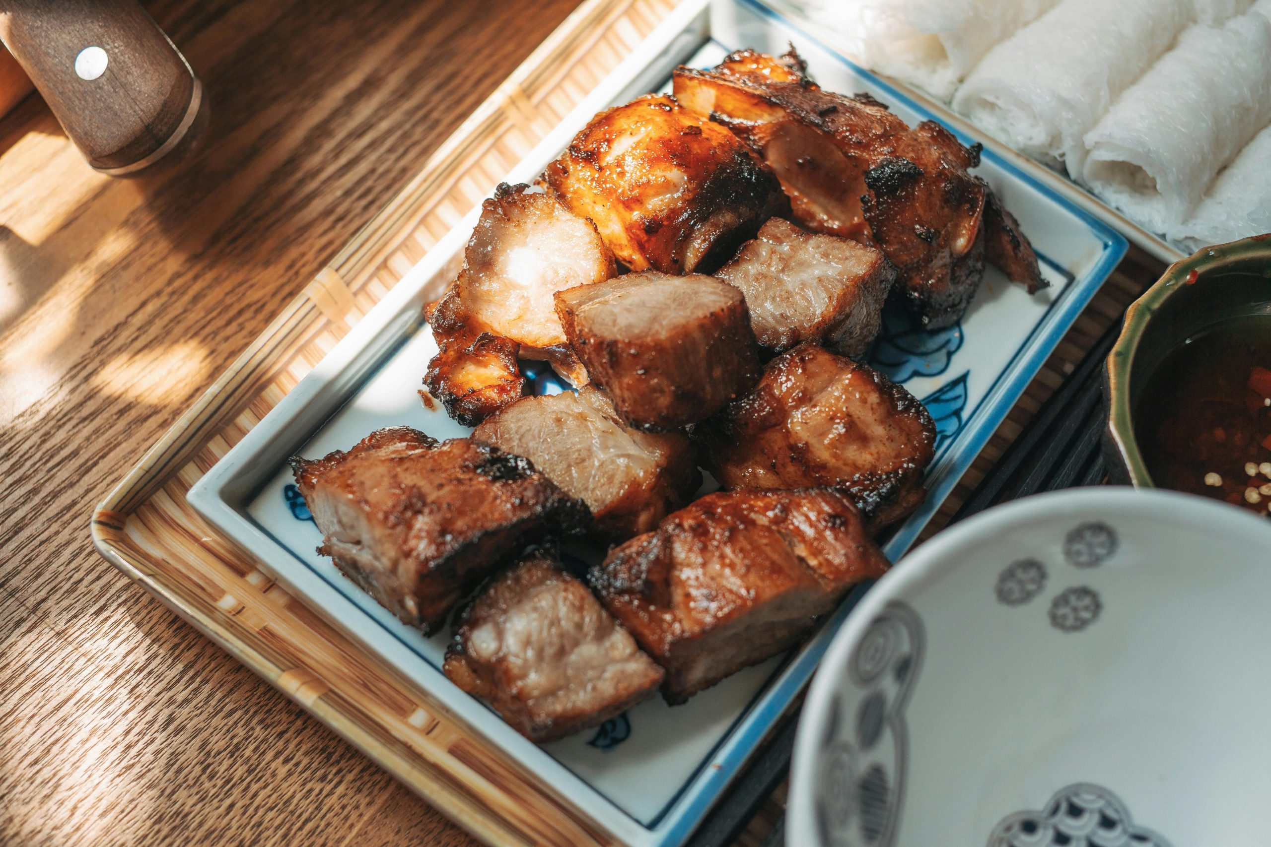 A plate of traditional Vietnamese 'Com Chay' (crispy scorched rice) served with a bowl of savory goat meat sauce, on a rustic wooden table in a local restaurant in Ninh Binh