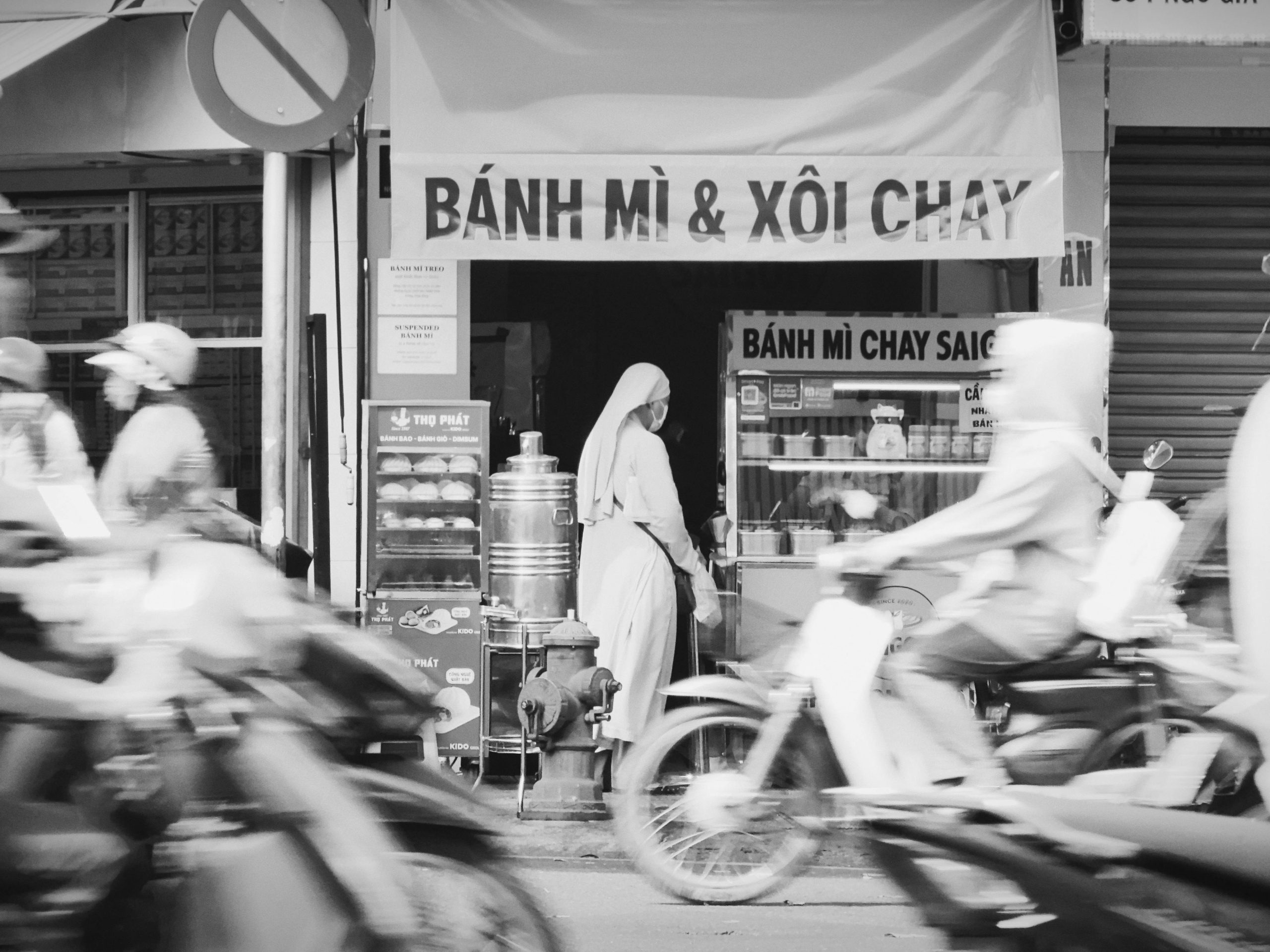 A vibrant street food stall in Ho Chi Minh City at night, illuminated by warm lights, showcasing various Vietnamese dishes like pho and banh mi, with locals and tourists enjoying their meals.