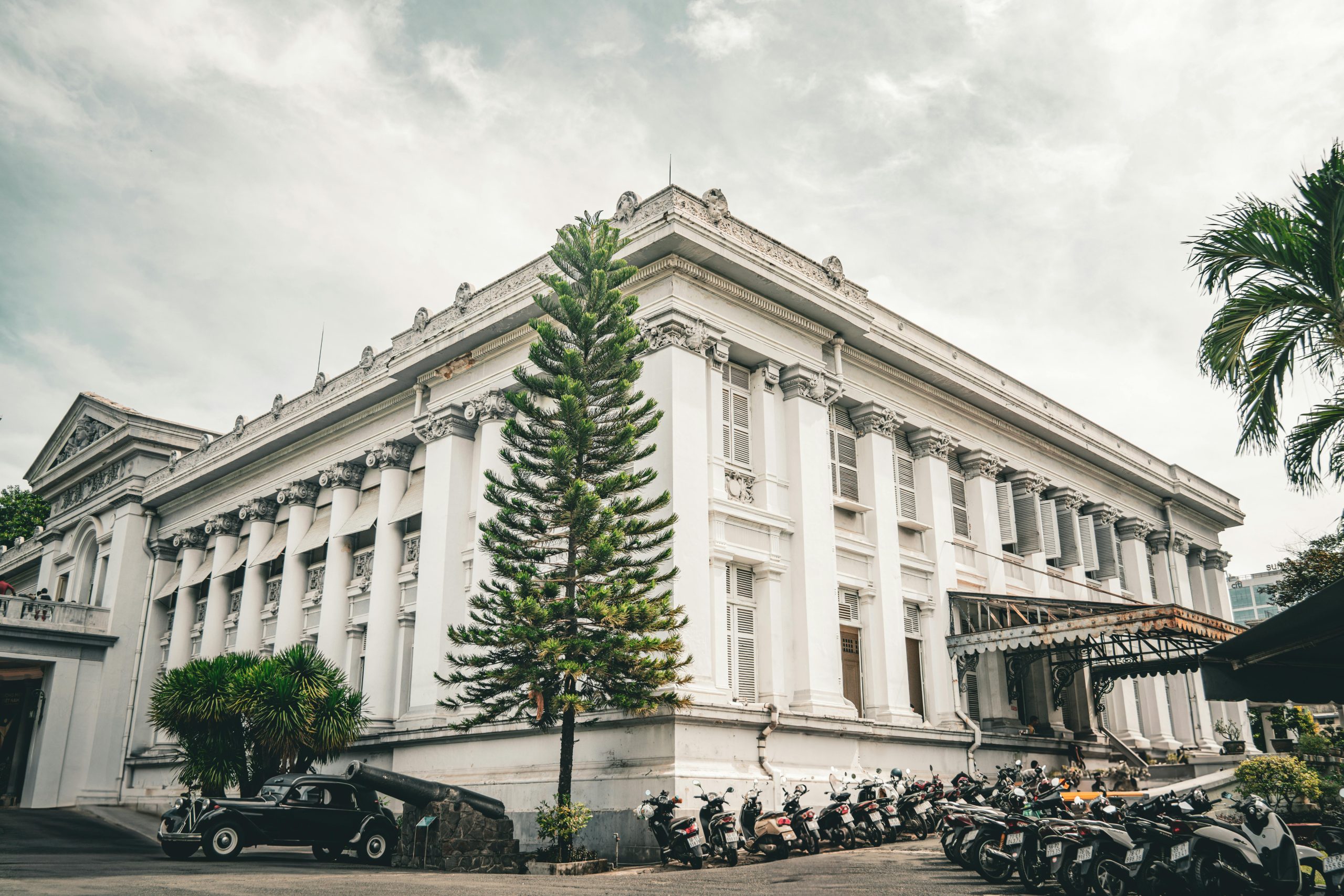 The elegant colonial-era architecture of the Southern Women's Museum in District 3, Ho Chi Minh City, featuring a white facade with green shutters, surrounded by well-maintained tropical greenery.