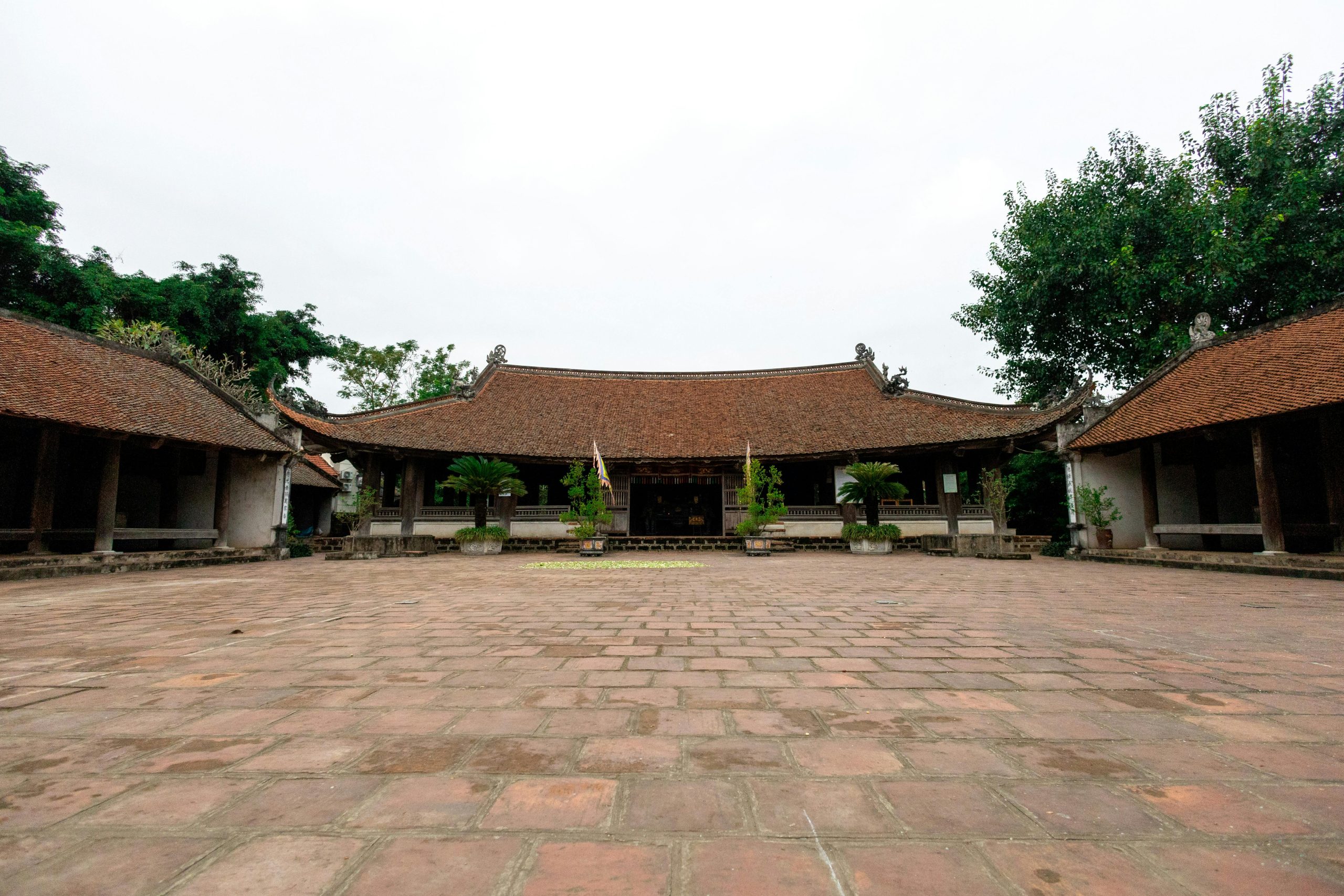 The tranquil courtyards of the Temple of Literature in Hanoi, featuring traditional Vietnamese architecture, lush greenery, and ancient stelae